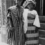 Vintage black-and-white photo of a couple in Yoruba attire, with a striped agbada and a patterned gele.