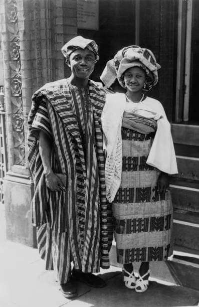 Vintage black-and-white photo of a couple in Yoruba attire, with a striped agbada and a patterned gele.