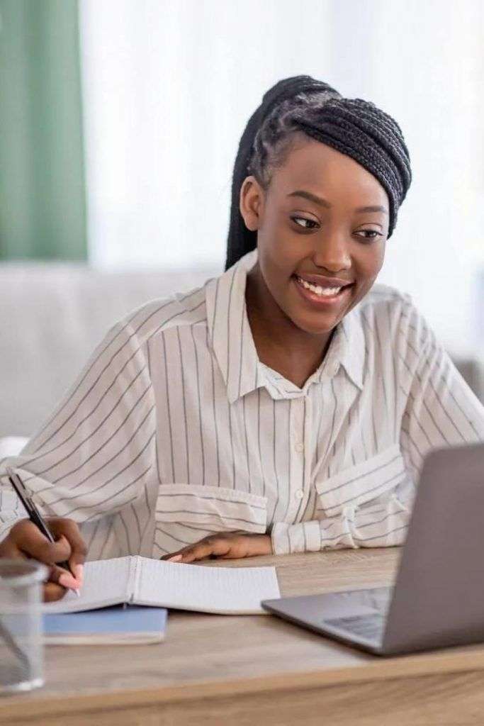 Woman taking notes while studying on her laptop for the IELTS exam